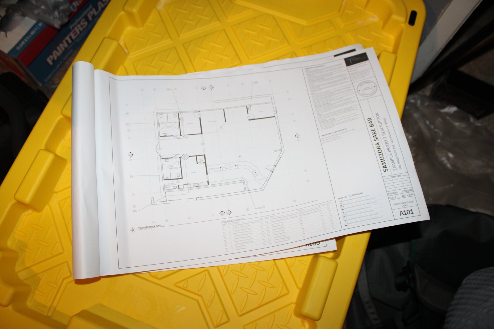A printed plan set open to the proposed floor plan sheet